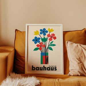 Pu&ograve; includere: Una stampa incorniciata con un design geometrico colorato di fiori in un vaso. La stampa ha il testo "botanisch bauhaus" in basso.