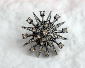 Spilla vintage da bavero color argento con fiocco di neve/stella polare e strass, in stile bigiotteria.