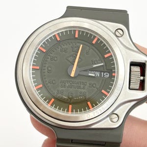 Könnte beinhalten: Eine weiße Keramik-Tasse mit schwarzem Henkel und dem Text "But First, Coffee" in schwarzer, fetter Schrift. Die Tasse steht auf einer weißen Oberfläche. Die Tasse ist etwa 10 cm hoch.