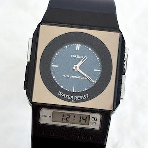 Könnte beinhalten: Eine schwarze Casio-Uhr mit quadratischem Zifferblatt und Digitalanzeige. Das Zifferblatt hat ein blaues Zifferblatt mit weißen Zeigern und Markierungen sowie den Text "ILLUMINATOR" und "WATER RESIST". Die Digitalanzeige zeigt die Uhrzeit 1:21:14 an.