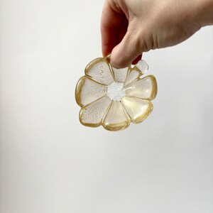 May include: A gold and clear glass flower-shaped dish with a textured surface.