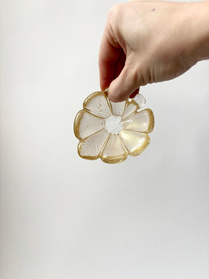 May include: A gold and clear glass flower-shaped dish with a textured surface.