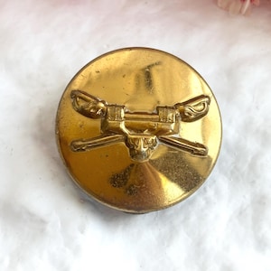 Pin de doble poste dorado con la imagen de un soldado de infantería del Ejército de EE. UU. de la Segunda Guerra Mundial con el tanque M26 sobre sables de caballería cruzados.
