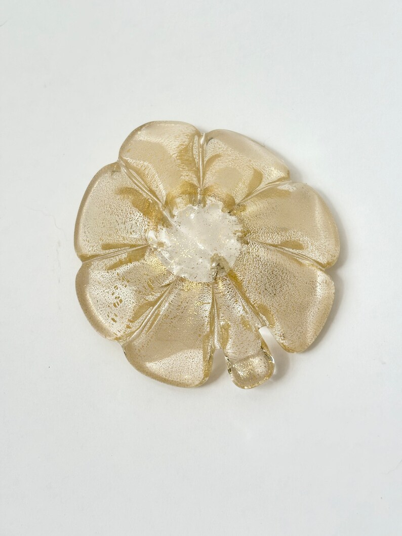 May include: A gold-colored glass flower-shaped dish with a textured surface.