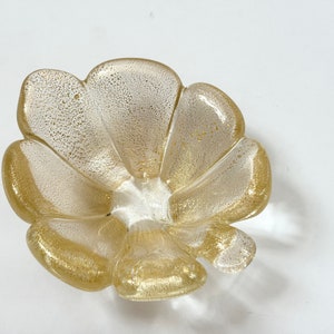 May include: A gold and white glass bowl shaped like a flower with five petals.