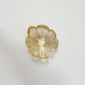 May include: A gold-colored glass dish shaped like a flower with five petals.