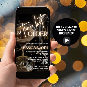 May include: A smartphone screen displaying a digital invitation for a 40th birthday party. The invitation features a cocktail glass with a gold rim and the text "a tiny bit older". The invitation also includes the party details: Jessica's 40th, Saturday February 10th, 7pm onwards, The Johnsons House, a really lovely place, 123 Anywhere St, Any City. RSVP to Amy by Feb 3rd on XXX XXX XXXX. A play button icon is displayed on the screen.