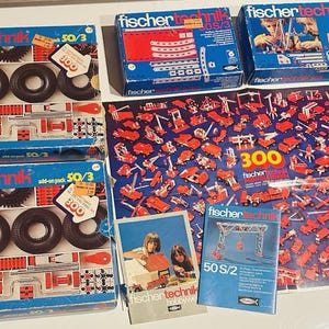 Puede incluir: Un conjunto de juegos de construcción Fischertechnik vintage, que incluye cajas azules con el logotipo y los números de producto de Fischertechnik. Los juegos incluyen neumáticos, engranajes y componentes de construcción. También se incluye un póster con 300 piezas.