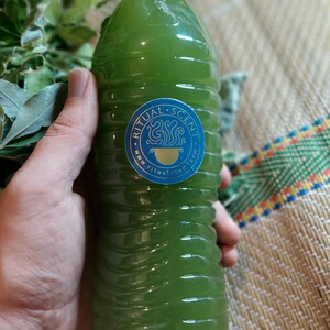 May include: A green liquid in a clear plastic bottle with a white cap. The bottle has a blue and gold sticker with the text "Ritual Scent" and "www.ritualscent.com".