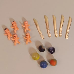 May include: A collection of miniature plastic baby dolls, gold-colored toy knives, and colorful glass marbles.