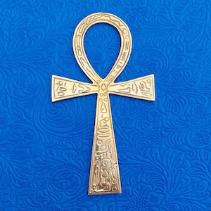 May include: A gold Ankh pendant with intricate hieroglyphics etched into the surface. The Ankh is a symbol of eternal life in ancient Egyptian mythology.