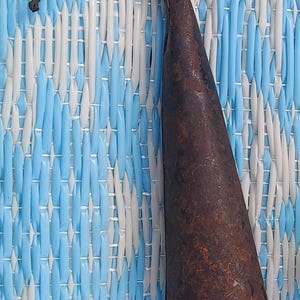 Może przedstawiać: Metalowy hak zardzewiały z zakrzywionym uchwytem. Hak jest ciemnobrązowy i ma ostry koniec.