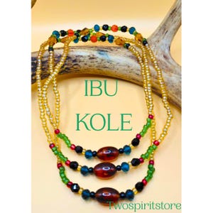 May include: Three strands of beaded jewelry with the text "IBU KOLE" in green. The strands are gold, with sections of red, green, black, and blue beads. The bottom right corner has the text "Twospiritstore".