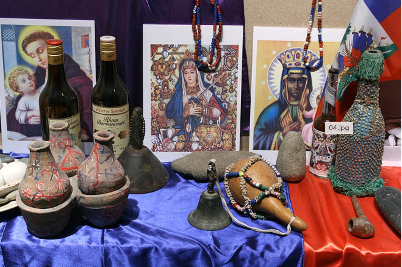 Haitian Vodou altar featuring bottles, images, beads, and offerings to the Loa.