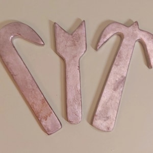 May include: Three metal hooks in different shapes. The hooks are a light silver color and have a smooth, polished finish.