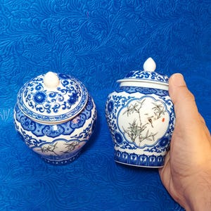 May include: Two blue and white porcelain jars with intricate floral and bamboo designs. The jars have lids and are decorated with traditional Chinese motifs.