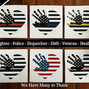 May include: Six printable heart-shaped designs featuring a black handprint with a US flag inside. Each heart has a different colored stripe across the bottom: red, blue, yellow, blue, red, and yellow. The text "Firefighter - Police - Dispatcher - EMS - Veteran - Healthcare" is printed below the top row of hearts. The text "We Have Many to Thank" is printed below the bottom row of hearts.