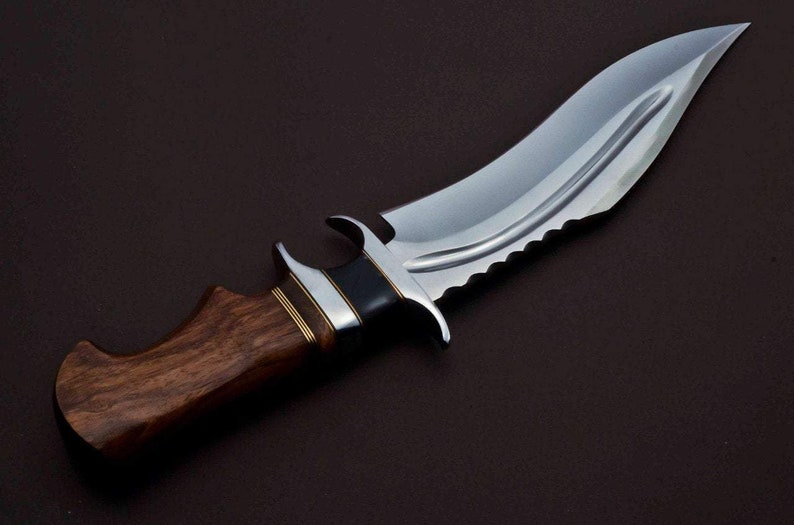 May include: A silver knife with a curved blade and a wooden handle. The blade has a serrated edge and a black accent near the handle.