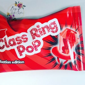 Puede incluir: Paquete rojo y negro para caramelos Class Ring Pop, edición de graduación. El paquete presenta un caramelo Ring Pop rojo con un gorro de graduación en la parte superior.