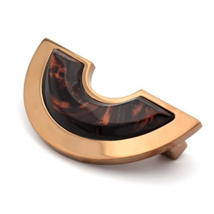 Op de afbeelding: Een gouden kastknop met een bruine, gemarmerde, halfronde inzet.