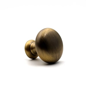 Peut inclure: Un bouton de meuble rond avec une finition en laiton antique brossé. La quincaillerie présente une surface avant bombée et lisse ainsi qu'une base circulaire effilée qui se connecte au point de fixation, révélant une texture métallique.