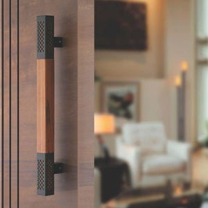 May include: A black and wood door handle with a geometric pattern. The handle is mounted on a wooden door.
