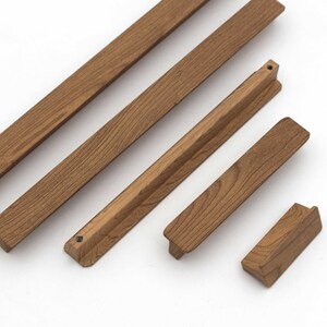 May include: A collection of wooden furniture components in various shapes and sizes. The pieces are a warm brown color, with visible wood grain. The components include long, rectangular strips and shorter, angled pieces, suggesting a DIY furniture project.