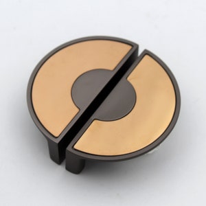 May include: A pair of round, split cabinet door pulls with a brushed nickel finish and a copper accent. The pulls are designed to be installed on the edge of a cabinet door.