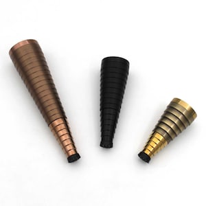 May include: Three cone-shaped furniture leg caps in different finishes: copper, black, and gold. Each cap has a series of concentric rings.