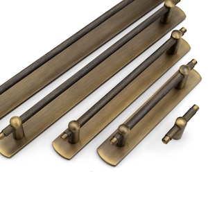 以下が含まれることがあります： テクスチャ加工が施され、丸みを帯びた端を持つ、アンティークブラス製のキャビネットプルが4つ。プルは長さが異なり、シンプルでモダンなデザインです。