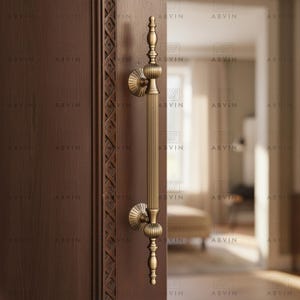 Könnte beinhalten: Ein bronzefarbener Türgriff mit vertikalem, geriffeltem Design. Der Griff hat dekorative, abgerundete Akzente an der Ober- und Unterseite und ist an einer dunkelbraunen Holztür angebracht. Die Tür hat geschnitzte Details am Rand.