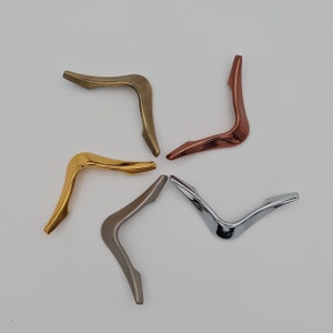 May include: Four cabinet door handles in different finishes: gold, silver, bronze, and chrome. The handles are shaped like a boomerang.