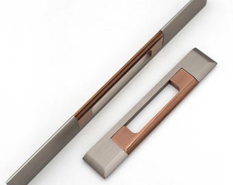 Puede incluir: Dos tiradores de armario modernos. El tirador largo mide 30 cm de largo y el tirador más corto mide 15 cm de largo. Ambos son una combinación de metal plateado cepillado y color cobre. Los tiradores tienen forma rectangular con un centro empotrado.