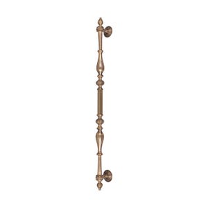 May include: Bronze-colored door pull with ornate detailing. The pull features a vertical design with decorative elements, including a central ribbed section and stylized finials at each end. Includes two circular mounting plates.