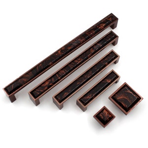 Könnte beinhalten: Satz von sechs Schrankgriffen in verschiedenen Größen mit einem Marmormuster in Schwarz- und Brauntönen. Die Griffe haben eine Kupfer-Oberfläche.