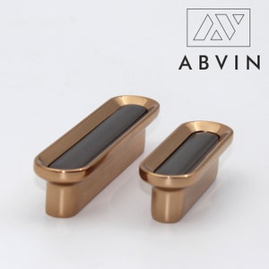 May include: Two bronze-colored cabinet pulls with a black center inlay. The pulls have a rectangular shape with rounded edges. The brand name "ABVIN" is displayed in black text above the pulls.