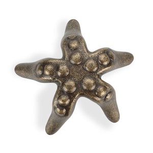 May include: Bronze-colored starfish-shaped decorative knob with a textured surface and raised circular details. The five-pointed star has a vintage, antique appearance. Ideal for coastal or nautical-themed decor.