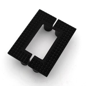 Peut inclure: Poignée de porte carrée noire avec un motif géométrique et une découpe rectangulaire.