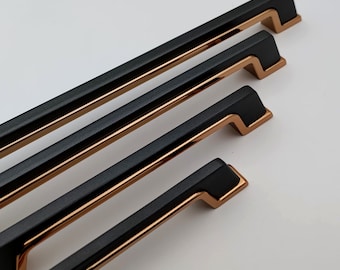 Peut inclure: Quatre poignées de meubles noires avec des accents cuivrés. Les poignées sont rectangulaires avec une poignée légèrement incurvée et un design moderne. Elles sont disposées en diagonale sur un fond blanc.