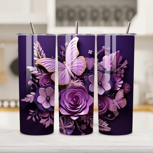 May include: A purple tumbler featuring a floral and butterfly design. The design includes purple roses, flowers, and butterflies with gold accents. The tumbler has a stainless steel straw and a lid.