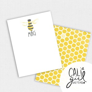 May include: White stationery with a watercolor bee illustration and the name "MAG" in black. The back of the stationery features a yellow honeycomb pattern. The Cali Girl Sketches logo is in the bottom right corner.