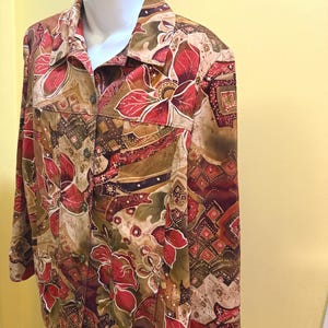 May include: A patterned jacket featuring a floral design in red, brown, and green hues. The jacket has a collared neckline and two front pockets. The material appears to be lightweight.