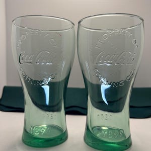 2 Vintage Coca-Cola Glasses with raised letters on both sides of the glass stating"Property of Coca Cola Bottling Co". 1899