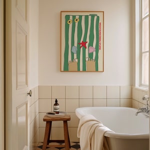 May include: A white bathtub with a white towel draped over the edge. A wooden stool with a bottle of soap and a brush sits next to the tub. A framed poster with green and white stripes and the text "WEAR SUNSCREEN, STUPID" hangs on the wall above the tub.