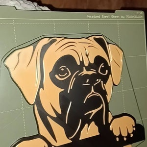 May include: A brown and black dog head key holder with three hooks. The dog is looking to the right and has a serious expression. The key holder is made of plastic and is printed with a 3D printer.