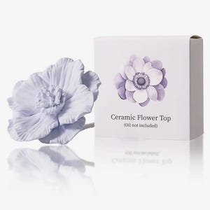 May include: A light purple ceramic flower top with a matching box. The box features a flower illustration and the text "Ceramic Flower Top (Oil not included)". The flower is a decorative item.