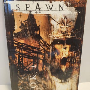 May include: A hardcover book titled "Curse of the Spawn: Sacrifice of the Soul." The cover features a dark, gothic illustration with a skeletal face, crosses, and a distressed, textured background in shades of brown and orange.