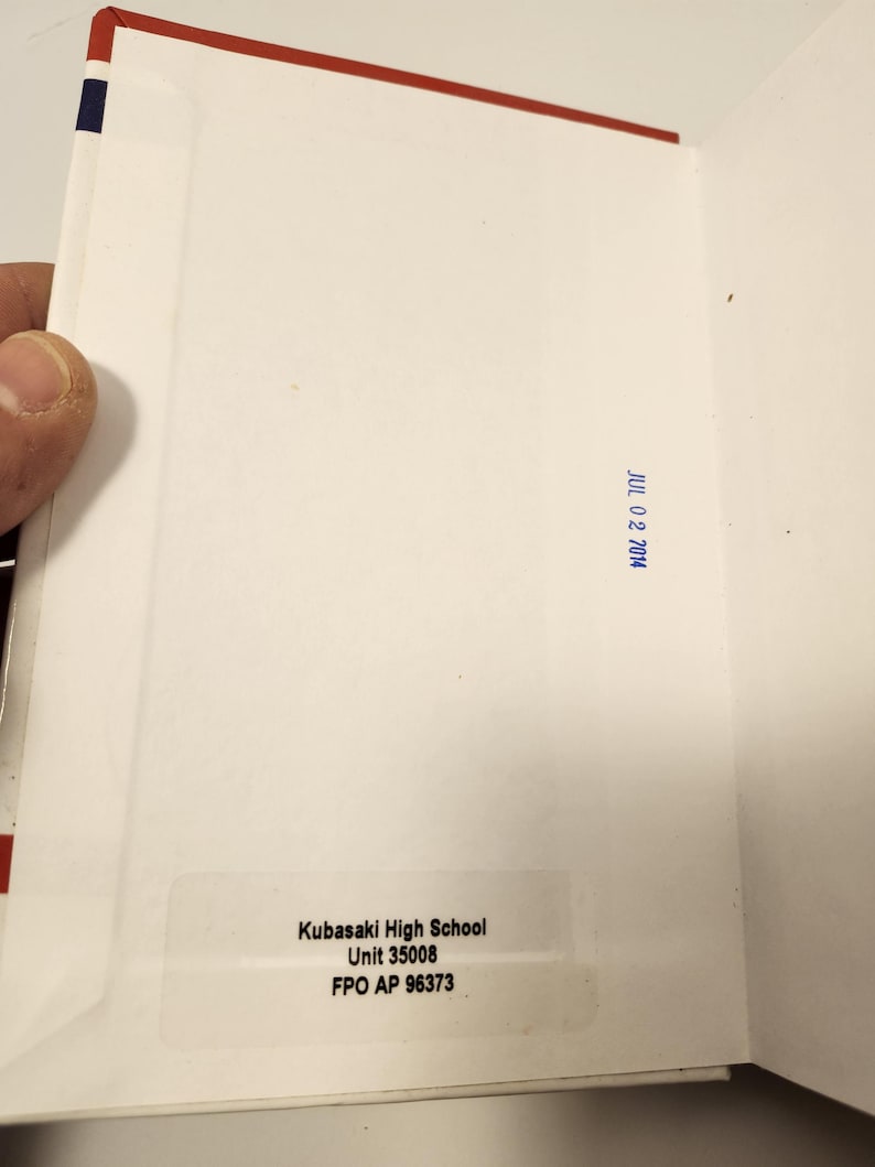 Puede incluir: Sobre blanco abierto con borde rojo y azul. El interior est&aacute; en blanco, con un sello azul que dice "JUL 02 2014". Una etiqueta muestra "Kubasaki High School, Unit 35008, FPO AP 96373."