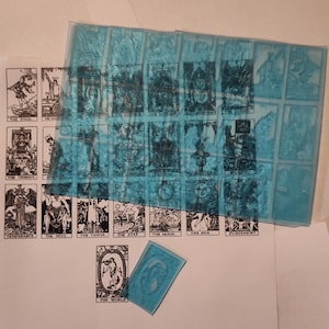 Może przedstawiać: Zestaw kart tarota z czarno-białymi ilustracjami. Karty ułożone są na białym tle z niebieskim nakładaniem. Karty obejmują Głupca, Maga, Rydwan, Diabła, Wieżę, Gwiazdę, Księżyc, Słońce, Sąd Ostateczny i Świat.