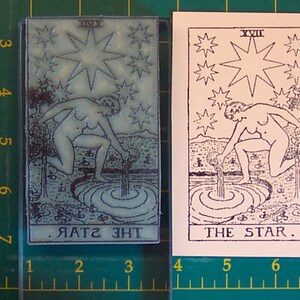 May include: A tarot card featuring an illustration of a nude figure pouring water into a pool, surrounded by stars. The card is labeled "THE STAR" and "XVII". The image is a print and a stamp.